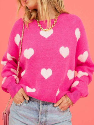 a woman wearing a pink sweater with white hearts on it