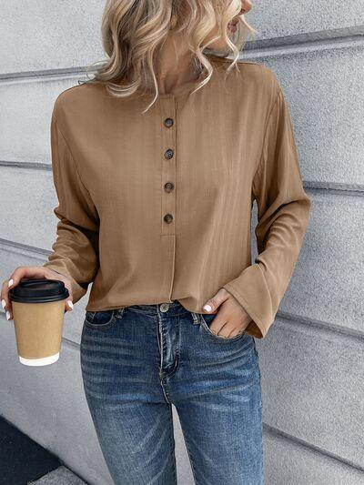a woman standing next to a wall holding a cup of coffee