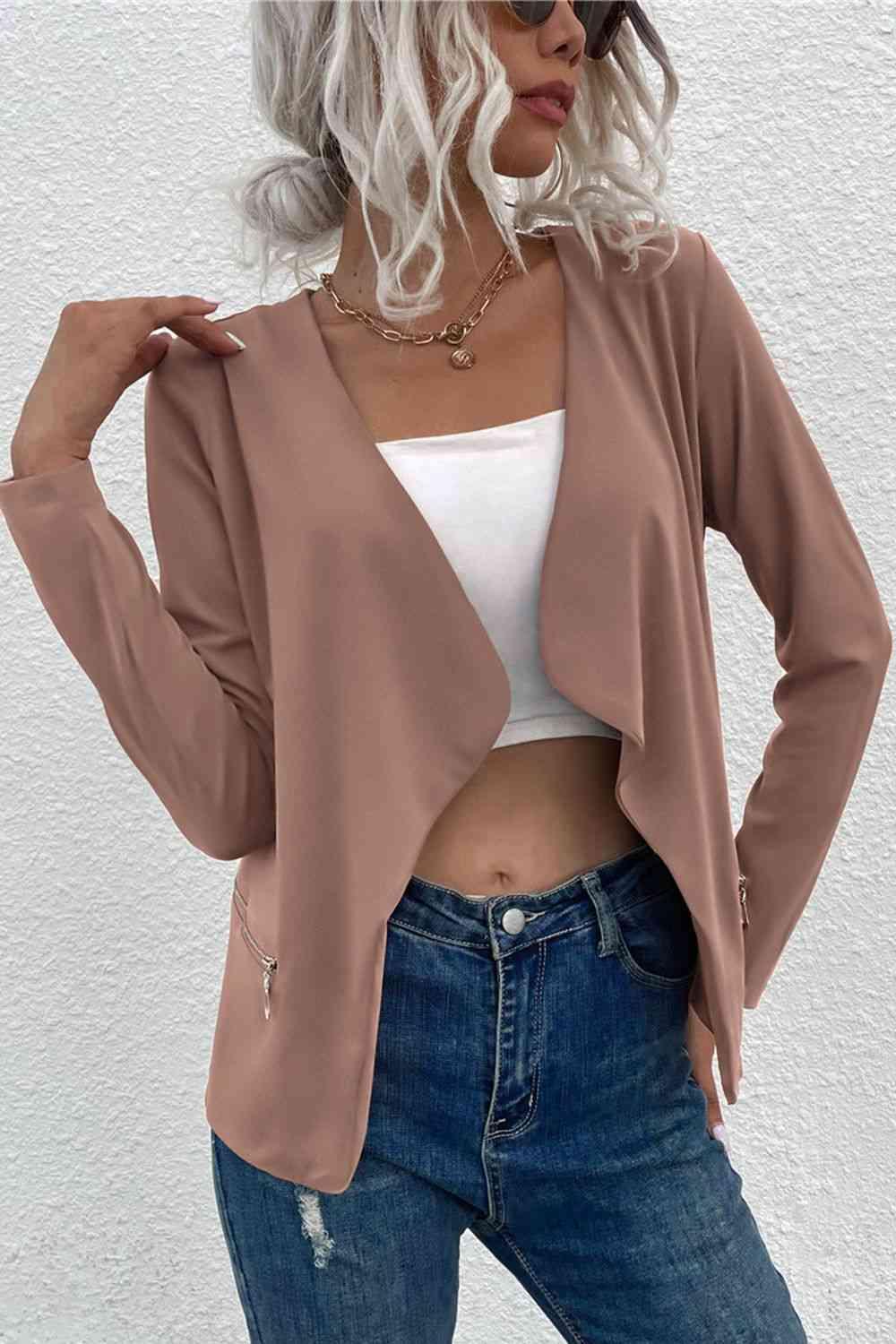 a woman with white hair wearing a tan jacket and jeans