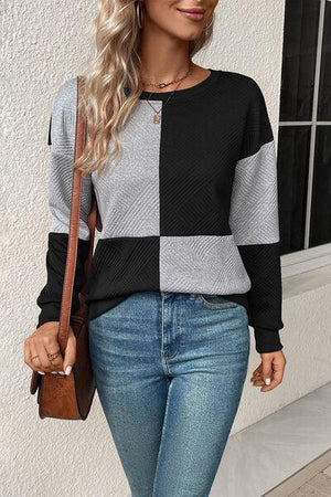 a woman wearing a black and grey sweater and jeans