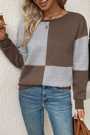 a woman wearing a brown and grey sweater
