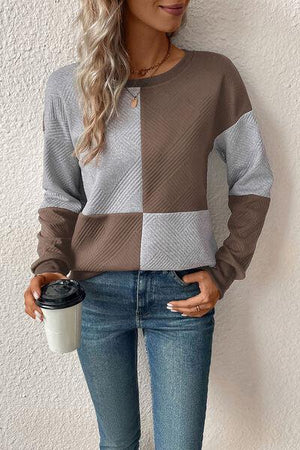 a woman holding a coffee cup and wearing a sweater