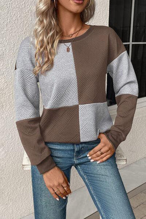 a woman wearing a brown and grey sweater