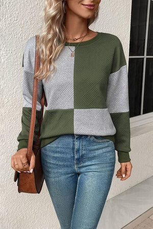 a woman wearing a green and grey sweater and jeans