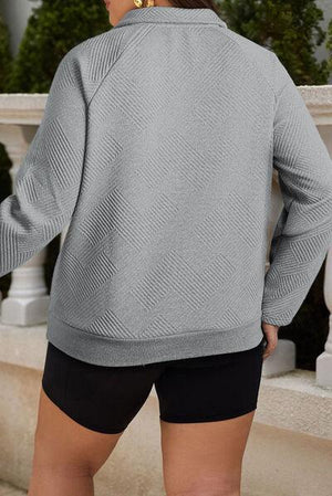 a woman wearing a grey sweater and black shorts