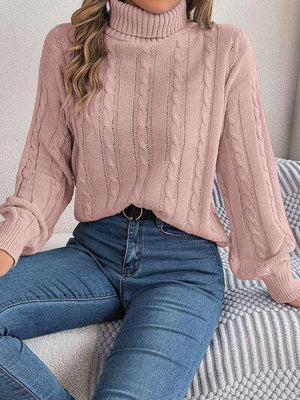 a woman sitting on a couch wearing a pink sweater and jeans