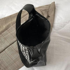 a black purse sitting on top of a bed