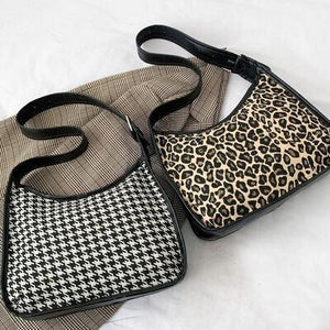 two purses sitting next to each other on a bed