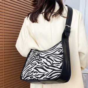 a woman is holding a zebra print purse