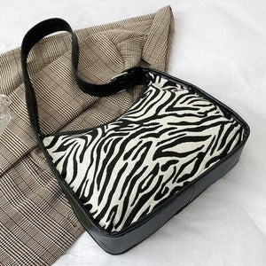 a zebra print bag sitting on top of a bed