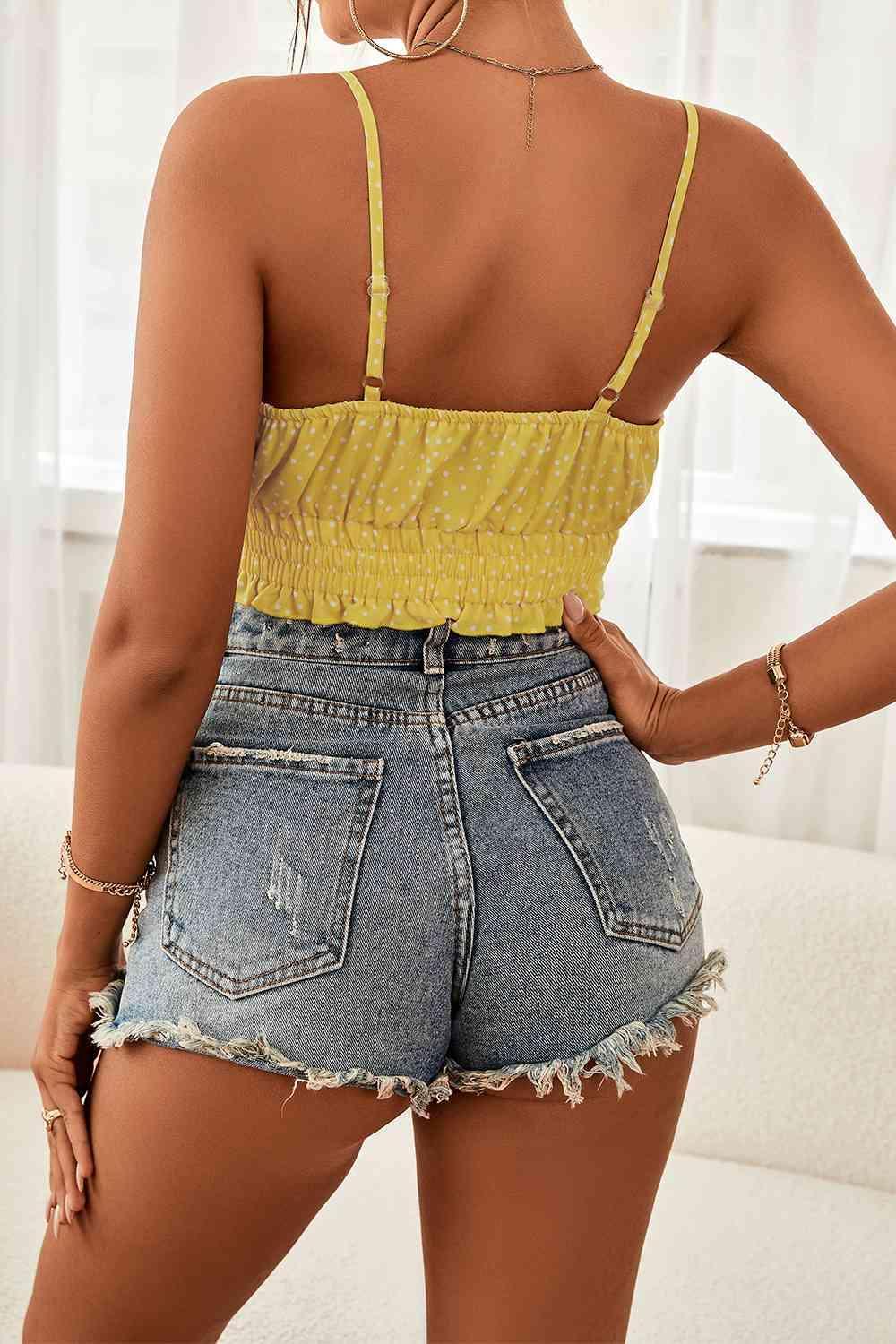 a woman wearing a yellow top and denim shorts