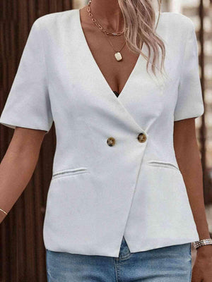 a woman wearing a white blazer and jeans