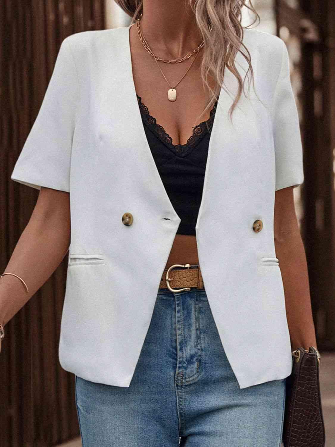 a woman wearing a white blazer and jeans