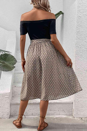 a woman in a black top and brown skirt