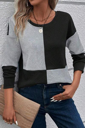 a woman wearing a black and grey sweater and jeans