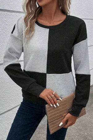 a woman wearing a black and white sweater and jeans