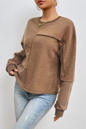 a woman wearing a brown sweater and jeans