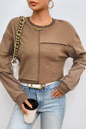 a woman wearing a brown top with a chain around her neck