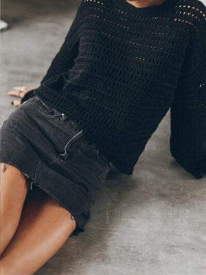 a woman sitting on the floor wearing a black sweater