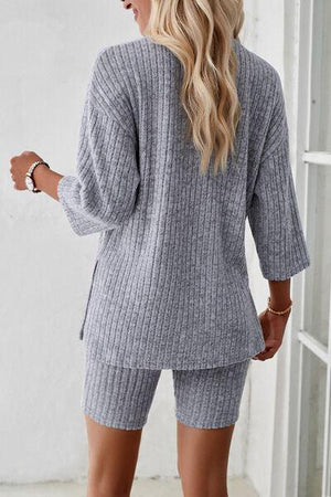 a woman wearing a grey sweater and shorts