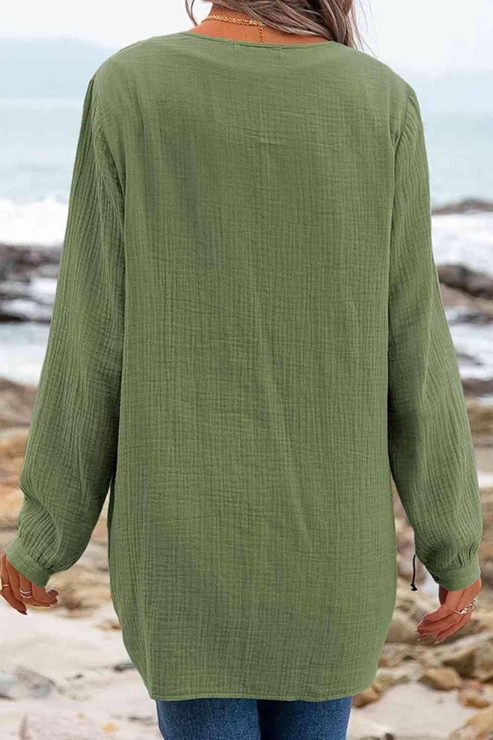 a woman standing on a beach wearing a green shirt