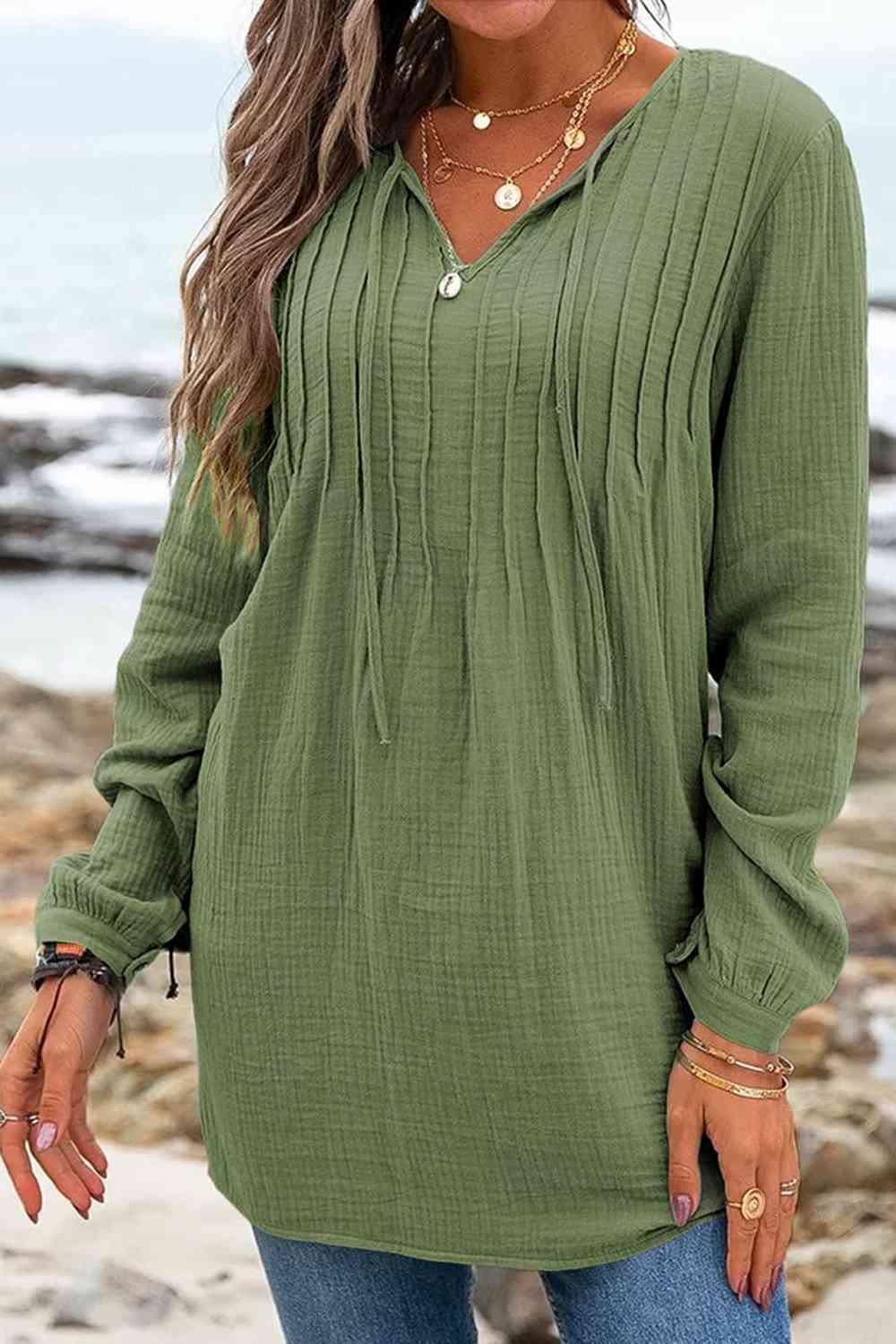 a woman standing on a beach wearing a green top