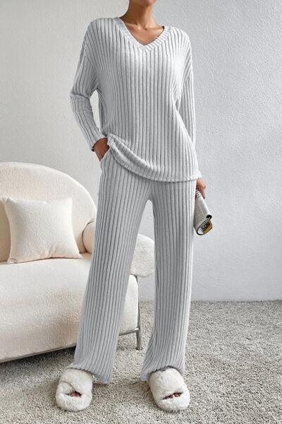 a woman standing in a room wearing a sweater and pants