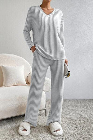 a woman standing in a room wearing a sweater and pants
