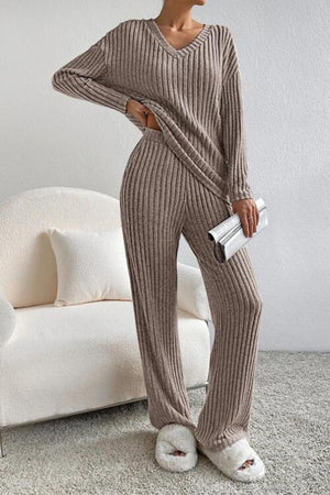a woman standing in a room wearing a sweater and pants