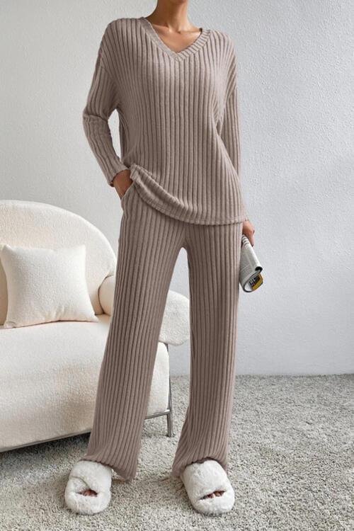 a woman standing in a room wearing a sweater and pants