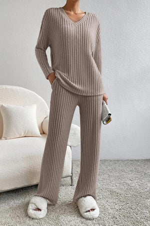 a woman standing in a room wearing a sweater and pants