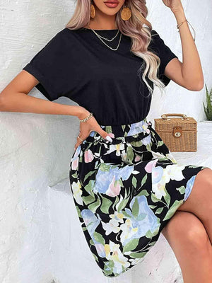 a woman wearing a black top and floral print skirt