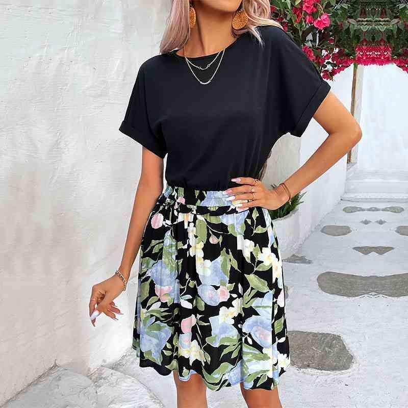 a woman wearing a black top and floral print skirt