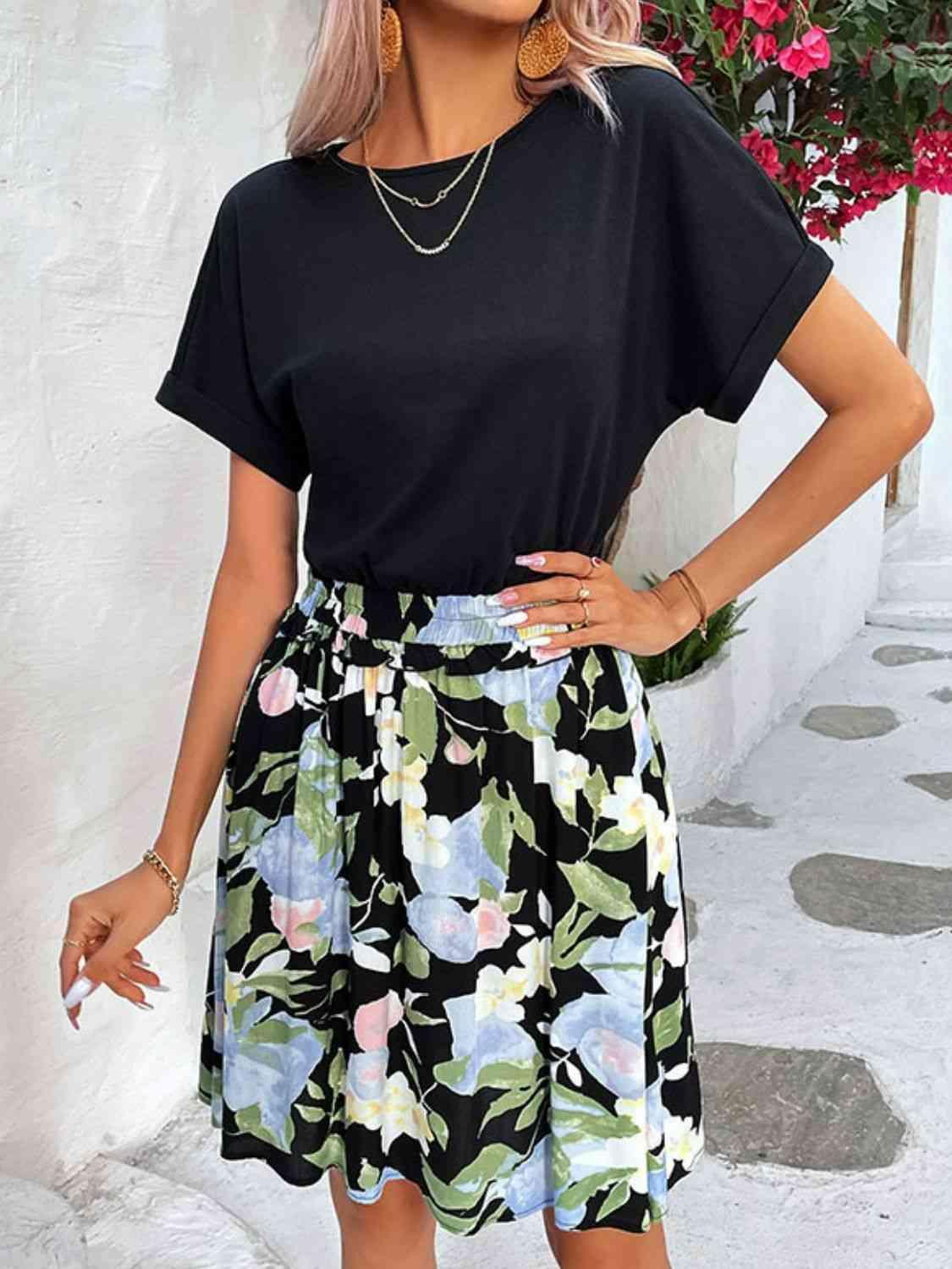 a woman wearing a black top and floral print skirt