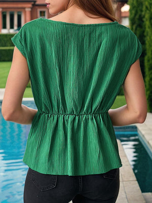 a woman standing next to a pool wearing a green top