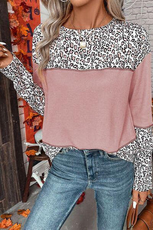 a woman wearing a leopard print top and jeans