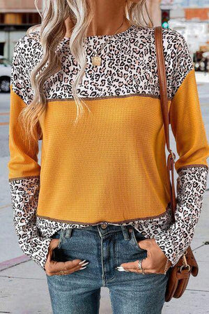 a woman wearing a leopard print sweater and ripped jeans