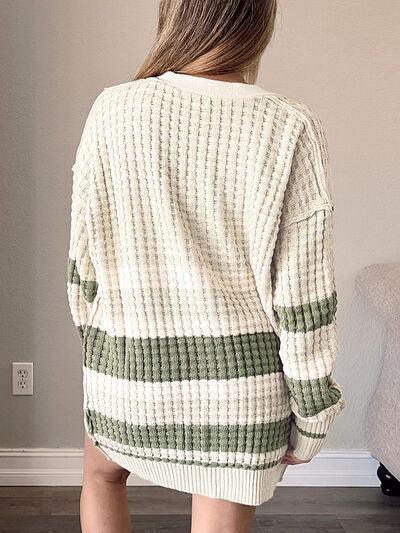 a woman standing in a room wearing a sweater