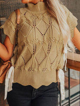 a woman wearing a tan sweater and black jeans