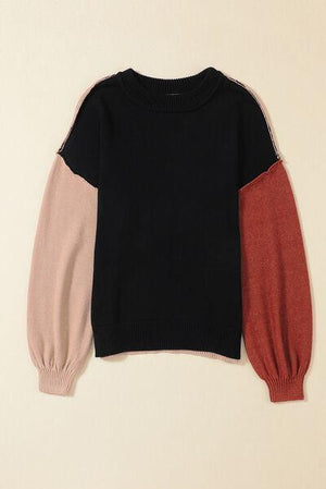 a black, pink, and red sweater hanging on a wall