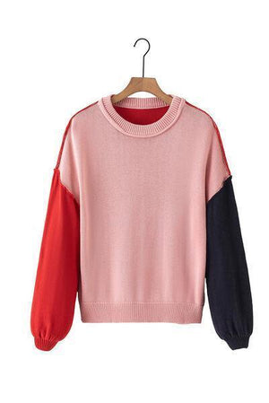 a pink and black sweater hanging on a hanger