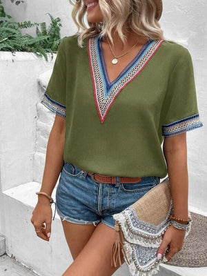 a woman wearing a green top and denim shorts