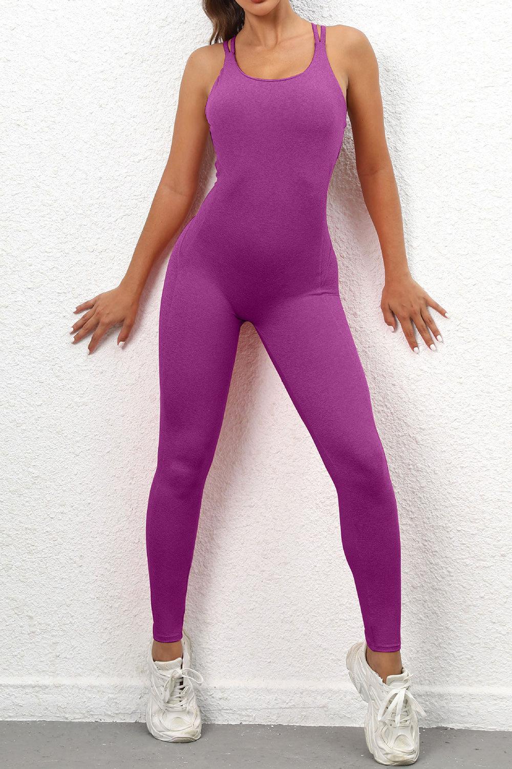 a woman in a purple bodysuit leaning against a wall