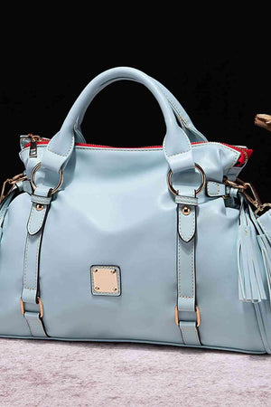 a light blue handbag with a tasseled handle