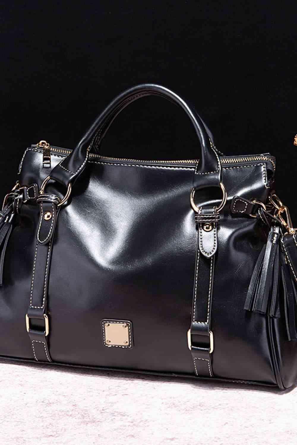 a black handbag with a tasseled handle