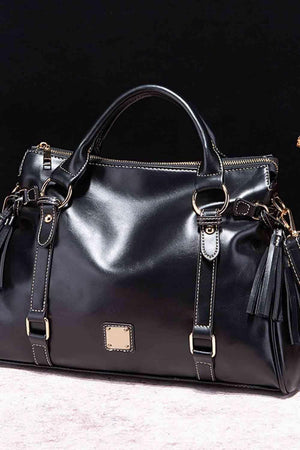 a black handbag with a tasseled handle