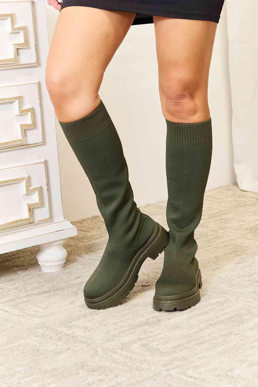 a woman wearing knee high socks and knee high boots