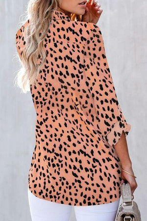 a woman wearing a leopard print top and white pants