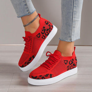 a woman wearing red sneakers with leopard print