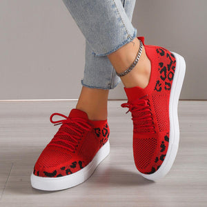a woman wearing red sneakers with leopard print